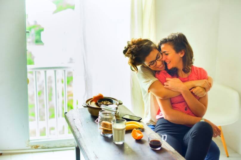 two women hugging each other at a breakfast table