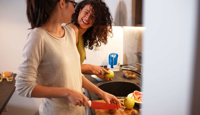 two women laughing and cutting fruit in a kitchen two women laughing and cutting fruit in a kitchen