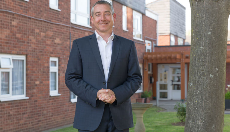 Man standing on a lawn in front of a bricked building Man standing on a lawn in front of a bricked building