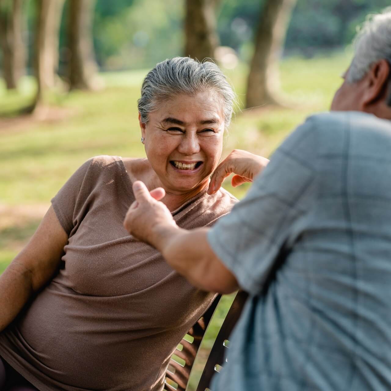 women sitting on the bench in a brown top smiling in conversation with a friend