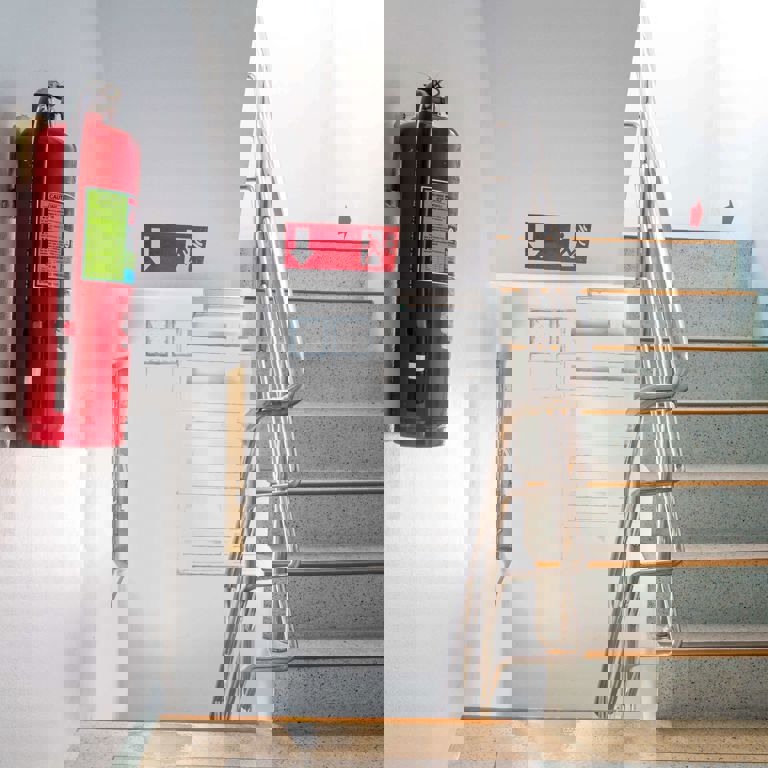 staircase with white walls leading to a evacuation door with red fire extinguisher on the wall staircase with white walls leading to a evacuation door with red fire extinguisher on the wall
