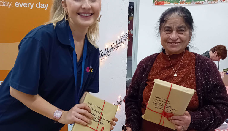 Two ladies holding wrapped gifts in brown paper and smiling Two ladies holding wrapped gifts in brown paper and smiling