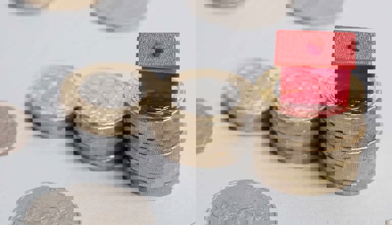 Pound coins stacked with a plastic red house on top Pound coins stacked with a plastic red house on top