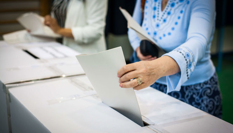 lady in blue shirt putting her vote in a voting box lady in blue shirt putting her vote in a voting box
