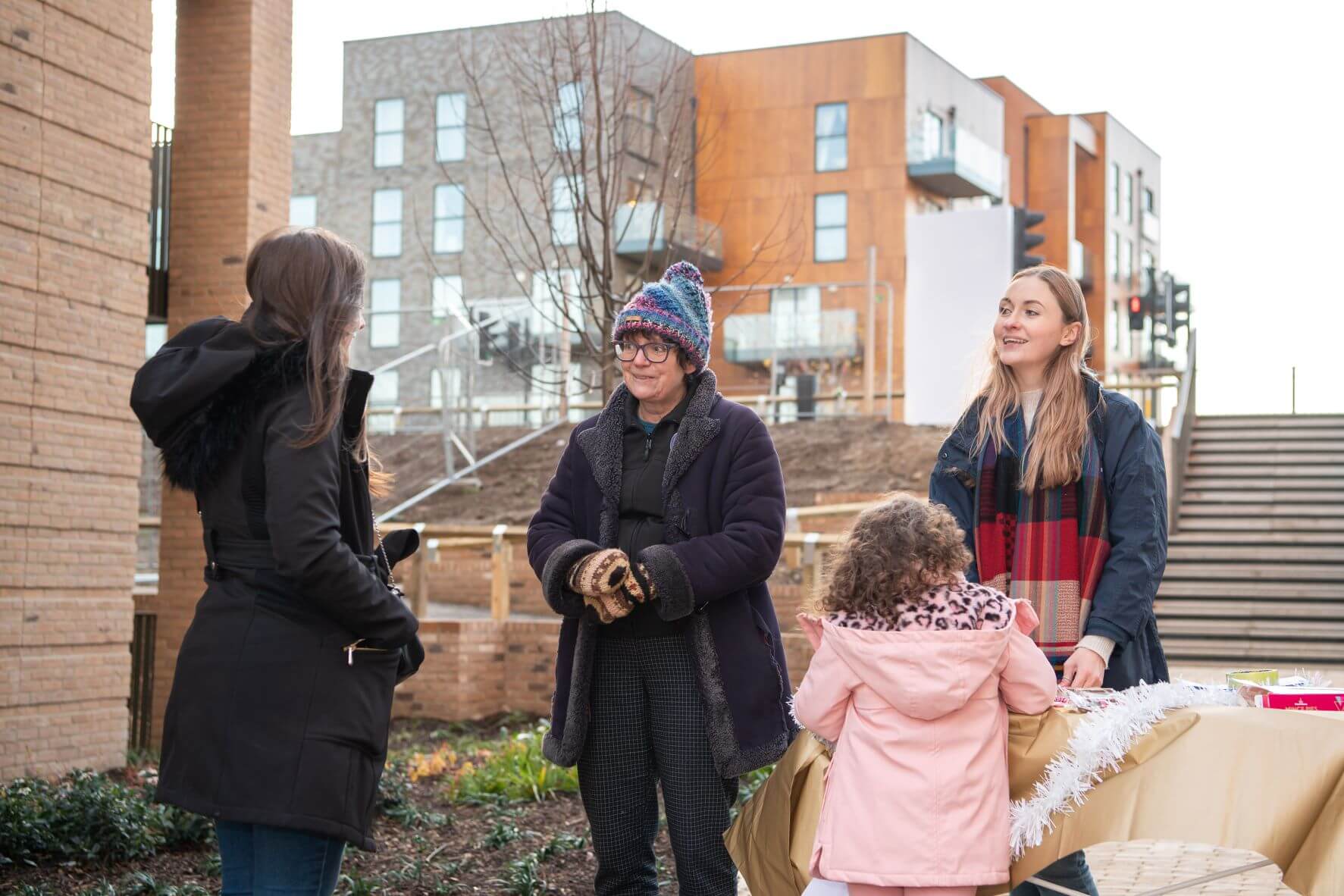 three ladies and a girl standing outside talking