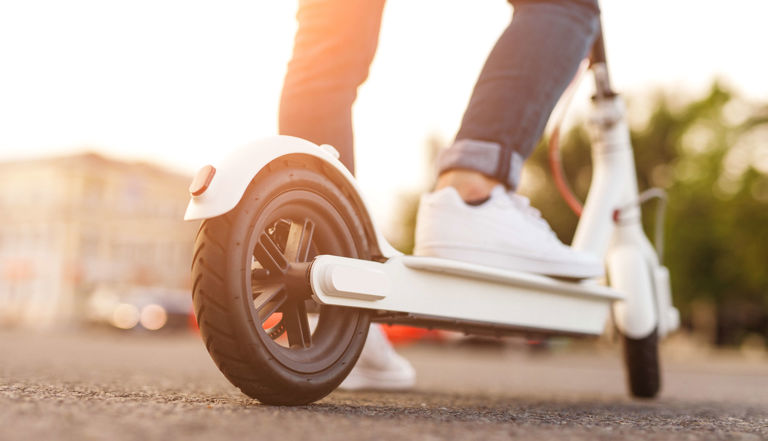 feet wearing white sneakers riding a white electric scooter feet wearing white sneakers riding a white electric scooter