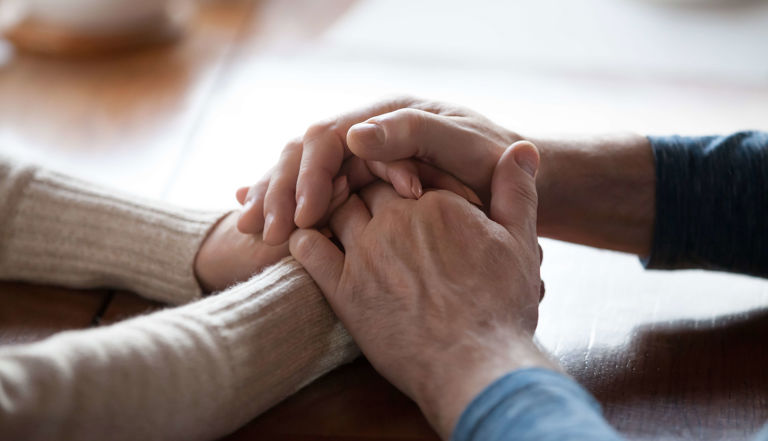 Image of two people holding hands supportively Image of two people holding hands supportively