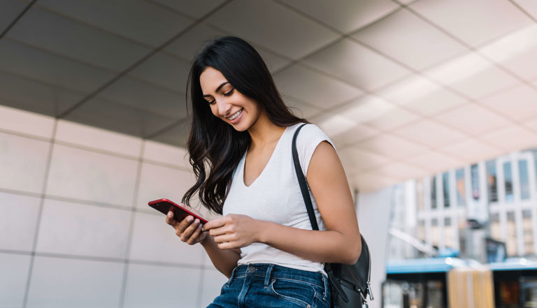 Woman smiling whilst looking at her mobile phone Woman smiling whilst looking at her mobile phone