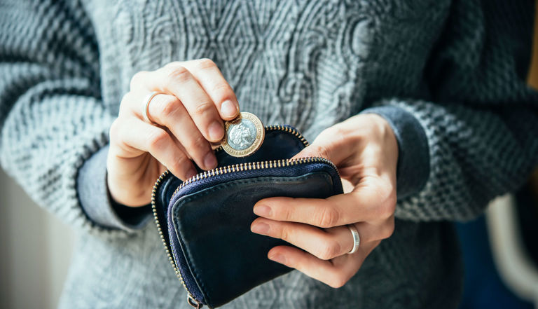 Woman putting a coin into a purse Woman putting a coin into a purse