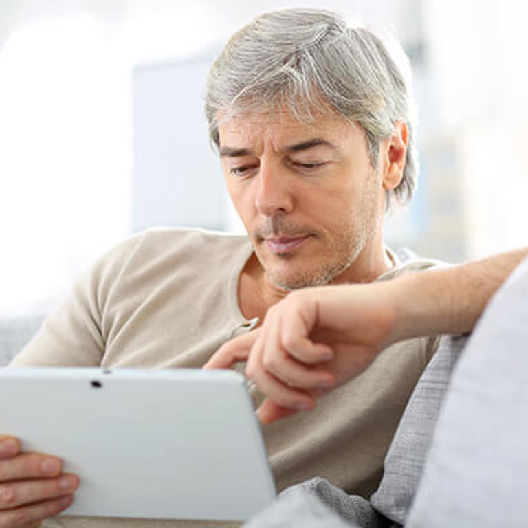 man sitting on couch typing on his tablet man sitting on couch typing on his tablet