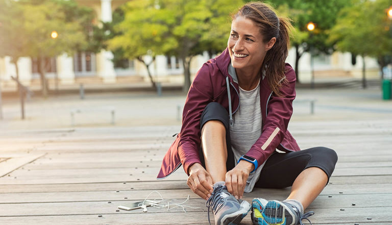 Lady sitting outdoors on the floor tying her shoelace Lady sitting outdoors on the floor tying her shoelace