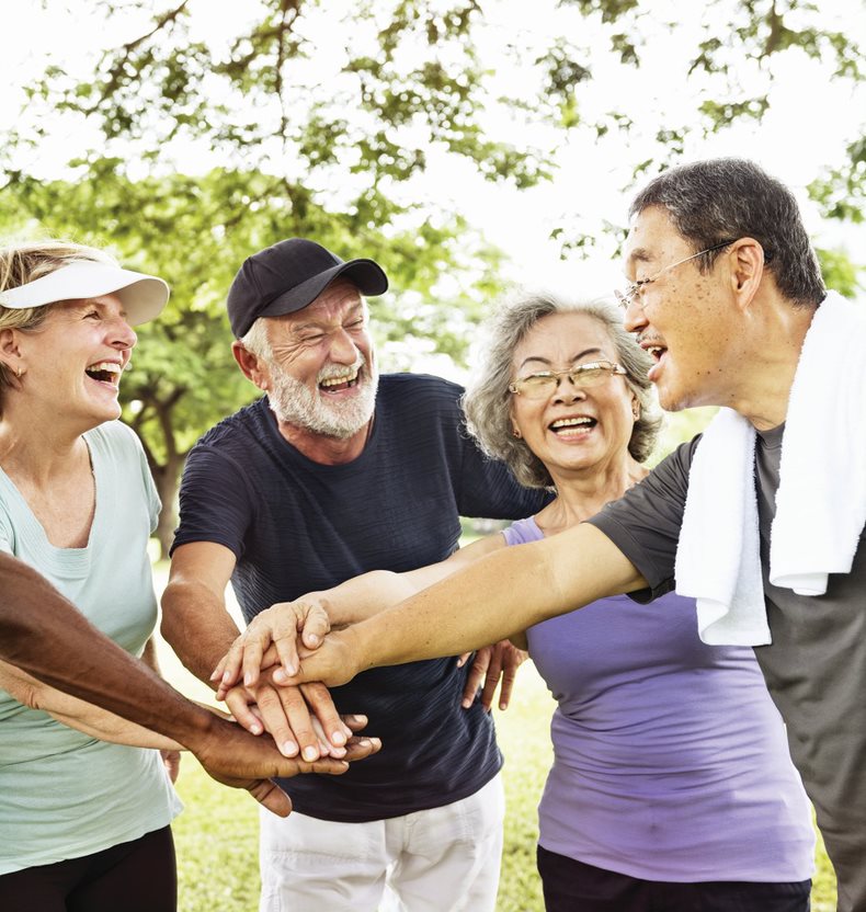 Four people joining hands on each other in a circle after exercising to show teamwork